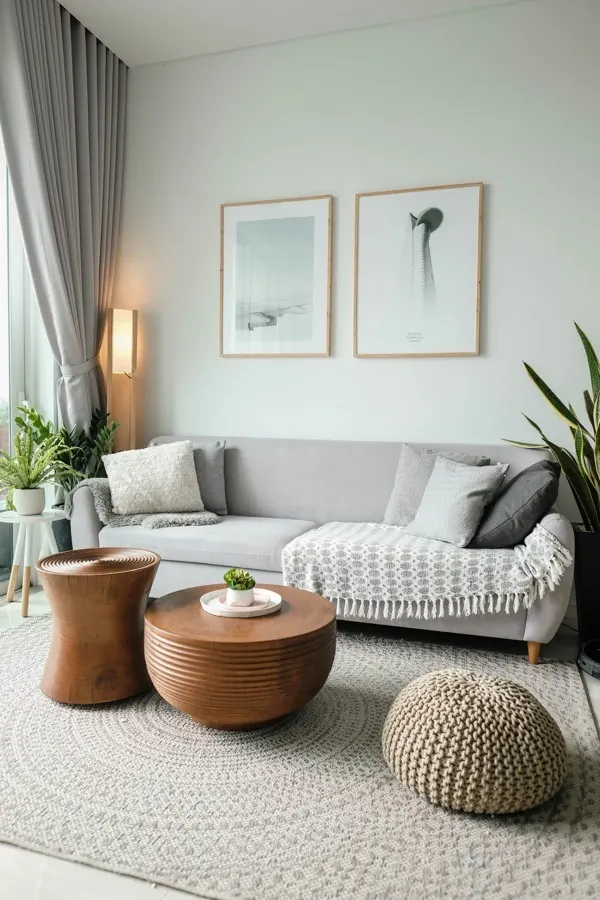 Living room with a knitted floor pouf on the rug and two framed prints above the sofa